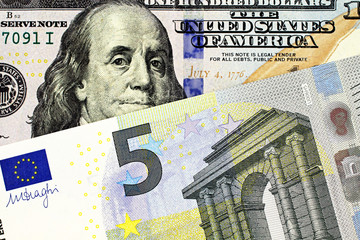 A close up image of a European Union five Euro note with an American one hundred dollar bill in macro