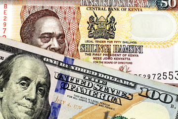 A close up image of a blue American one hundred dollar bill close up with a fifty Kenyan shilling bank note in macro