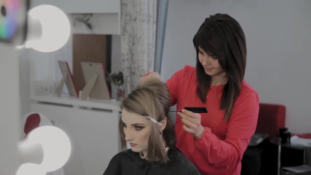 Professional hairdresser does a girl's hairstyle for a photo shoot.
