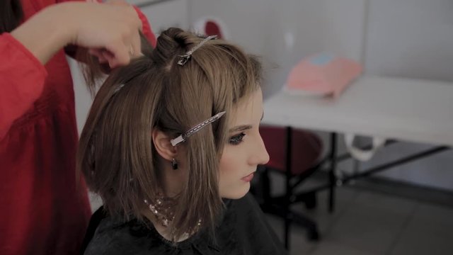 Professional hairdresser does a girl's hairstyle for a photo shoot.