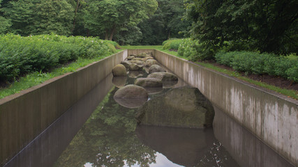 Pond channel with stones in park background