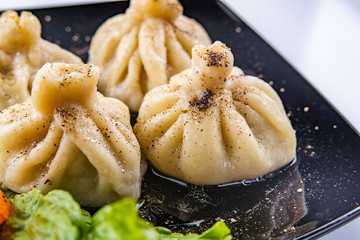 Georgian dumplings Khinkali with meat and red papper, on brown plate