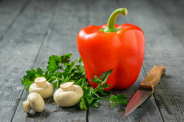 Beautiful red pepper with mushrooms and parsley on a wooden table. Vegetarian food.