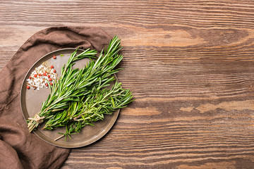Seasoning a bunch of fresh fragrant rosemary, salt, red peas on a brown wooden background. Copy space. View from above.