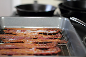 Cooked bacon in a baking tray out of the oven.