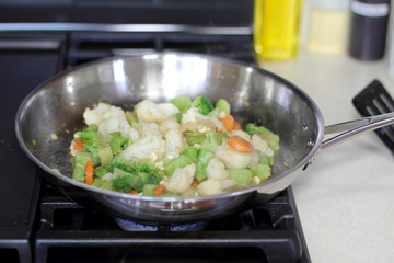 Vegetables cooking in a stainless steel pan.