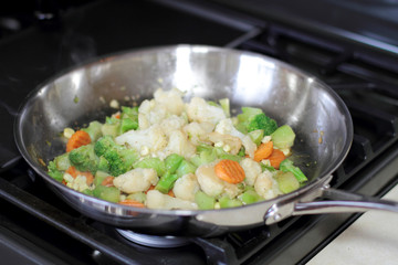 Vegetables cooking in a stainless steel pan.