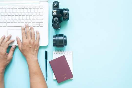 Top view of blogger's workspace desk with laptop, camera and passport. Travel concept