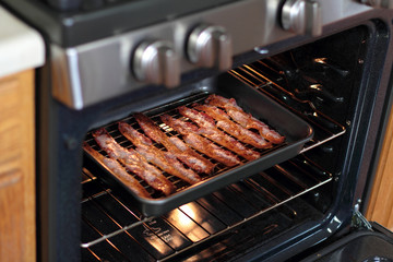 Cooked bacon in a baking tray out of the oven.
