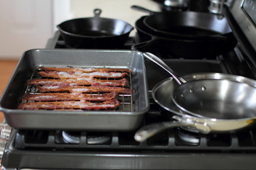 Cooked bacon in a baking tray out of the oven.