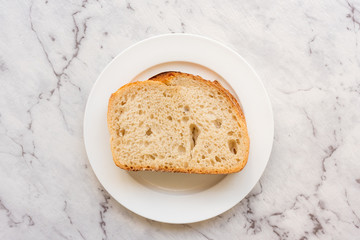 High angle view of sourdough bread on white plate against grey marble background