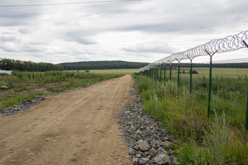 Fototapeta na wymiar Agricultural field, which is fenced with a net and between there is a field road