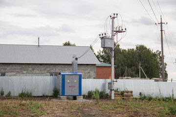 Fototapeta na wymiar Electric transformer in the field near the fence