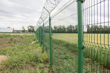 Agricultural field, which is fenced with a net and between there is a field road