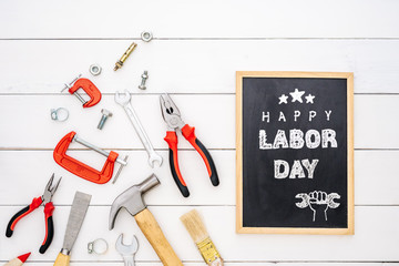 Happy Labor Day background concept. Flat lay of construction handy tools with black chalkboard with happy labor day text over wooden floor background.