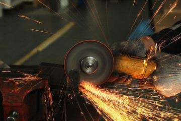 worker in gloves at the enterprise works as a grinder