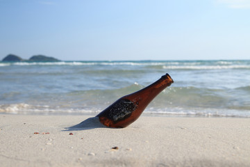 Fototapeta na wymiar Glass bottle garbage with clams on the beach background