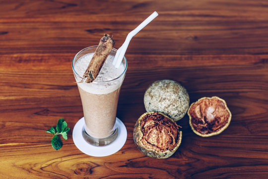 Wood apple or Limonia drink in glass on wooden table with fruits and cinnamon