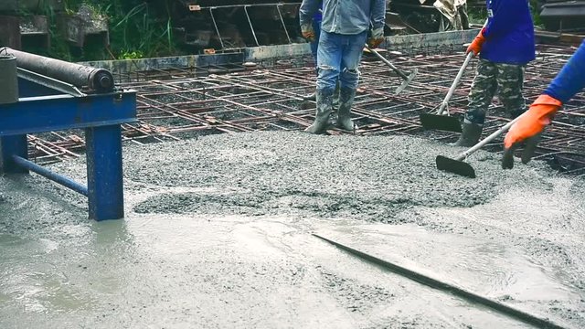 Man worker using a concrete steel basket for cement after Pouring ready-mixed concrete on steel reinforcement to make the road by mixing mobile the concrete mixer.