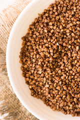buckwheat in bowl on wooden background.