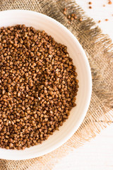 buckwheat in bowl on wooden background.