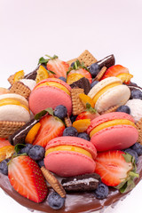 Cake with chocolate drips garnished with berries and macaroons