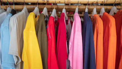 Fashion clothes on clothing rack - bright colorful closet. Closeup of rainbow color choice of trendy female wear on hangers in store closet or spring cleaning concept. Summer home wardrobe