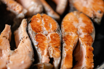 Close-up of roasted salmon steaks in a frying pan, top view. Fresh seafood for frying.