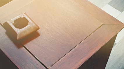 Wooden ashtray is placed on the wooden table.