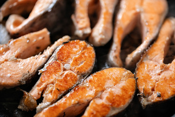 Close-up of roasted salmon steaks in a frying pan, top view. Fresh seafood for frying.