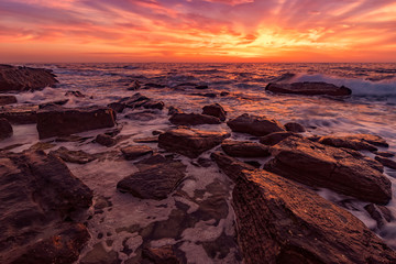 Fototapeta na wymiar Rocks on the stone beach at sunset. Twilight sea and sky. Dramatic sky and clouds. Nature landscape.
