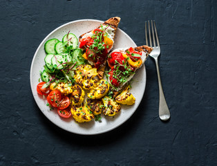 Healthy vegetarian snacks - turmeric baked cauliflower and marinated pepper, goat cheese, whole grain bread sandwiches on a dark background, top view