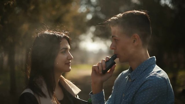 cute vaping couple standing in the park and talking