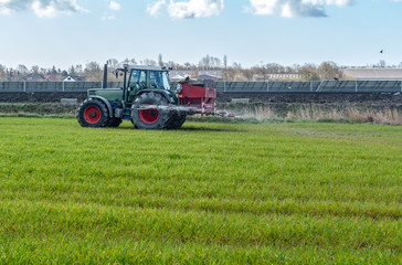 Fototapeta na wymiar Traktor mit Düngerstreuer auf dem Feld