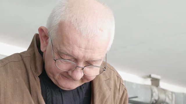 Serious old engineer in glasses at working. Portrait close up.