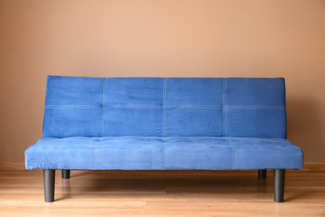 Stylish blue sofa near color wall in room