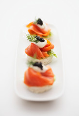 Cocktail blinis with crayfish, caviar and sour cream. Toast appetizer of salmon and caviar on a...