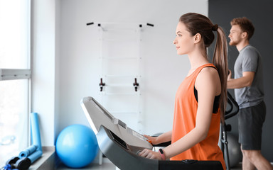 Fototapeta premium Sporty young woman training on treadmill in gym