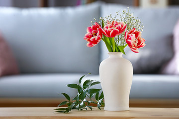 Vase with bouquet of beautiful flowers on table in room
