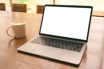 Fototapeta premium Mockup image of laptop with blank white desktop screen with coffee cup on wooden table