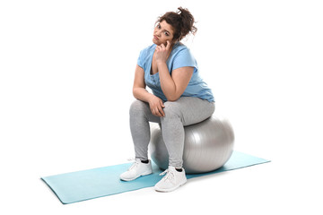 Displeased overweight woman sitting on fitball against white background