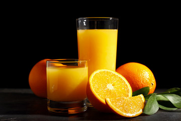 Glasses of orange juice on dark background