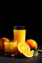 Glasses of orange juice on dark background