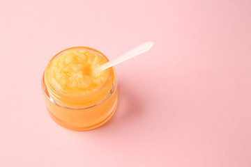 Jar of sugar scrub on color background