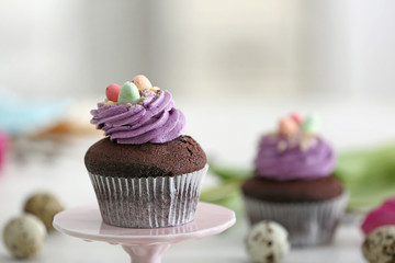 Dessert stand with sweet Easter cupcake on blurred background