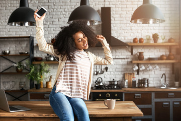 African-American woman listening to music in kitchen