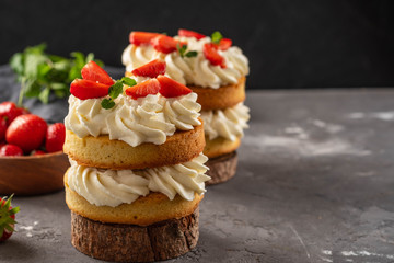 Victoria sponge cake with strawberries, jam and whipped cream on dark background. Copy space.