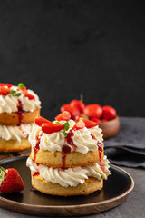 Victoria sponge cake with strawberries, jam and whipped cream on dark background. Copy space.