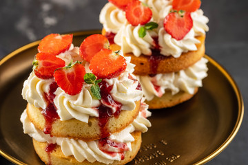 Victoria sponge cake with strawberries, jam and whipped cream on dark background. Copy space.