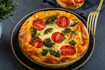 Vegetable pie with broccoli, tomatoes on the table close-up. Copy space.